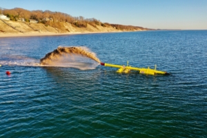 sand and water shooting from pipe in lake